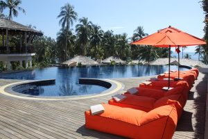 Piscina de un hotel de todo incluido con hamacas y sombrillas junto al edificio