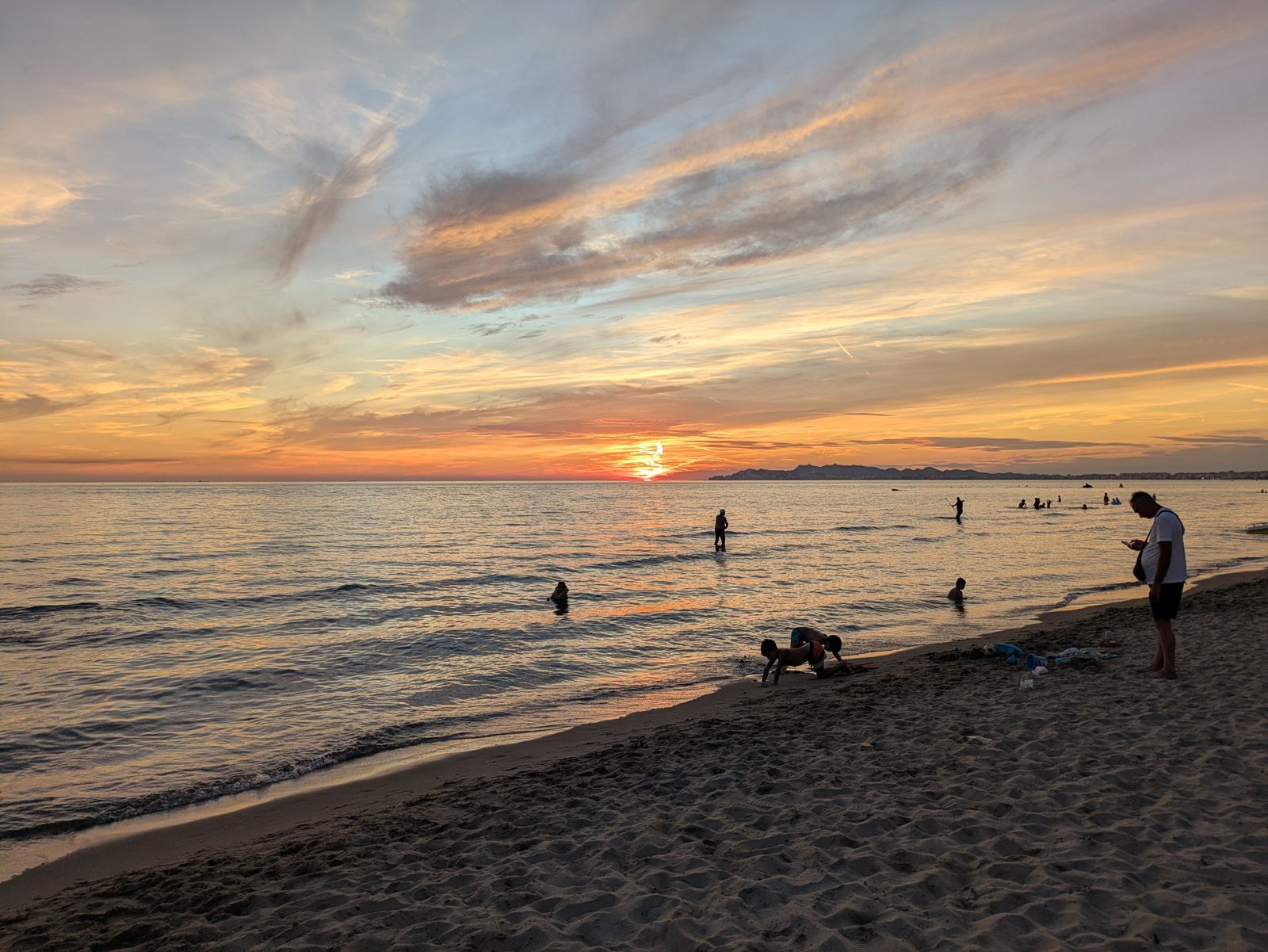 Atardecer sobre el Adriático en la playa de Durrës, con bañistas en la orilla