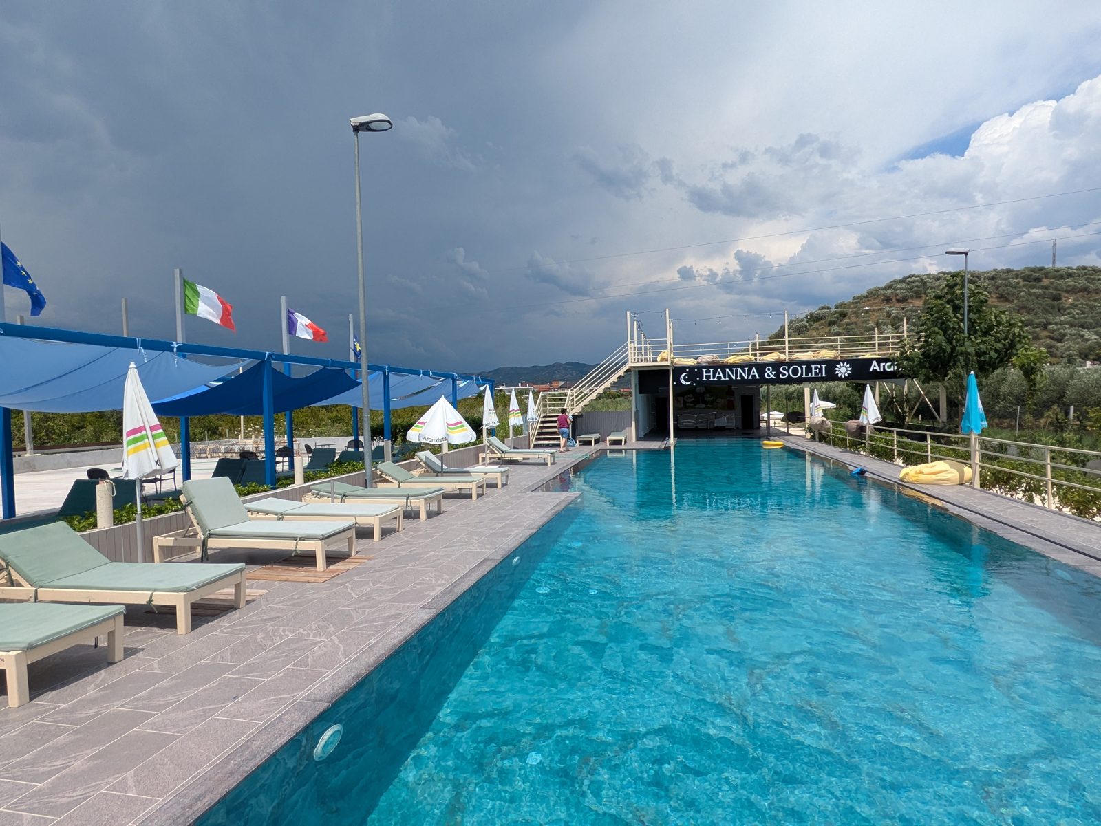 Piscina del Hanna & Solei Hotel, cerca de Berat, con tumbonas y montañas al fondo