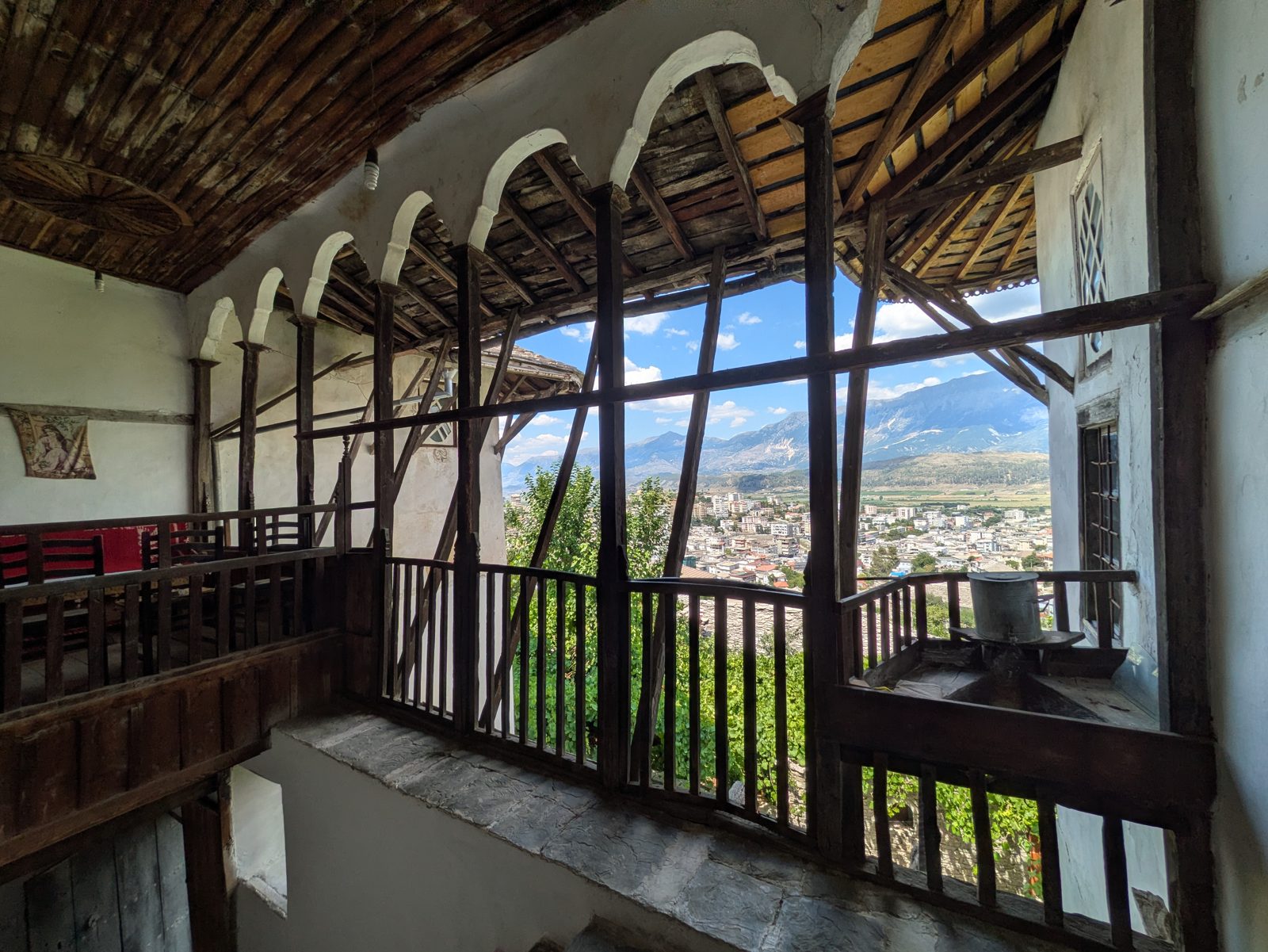 Ventanal de madera de la Casa Skënduli con vistas a los tejados y al valle