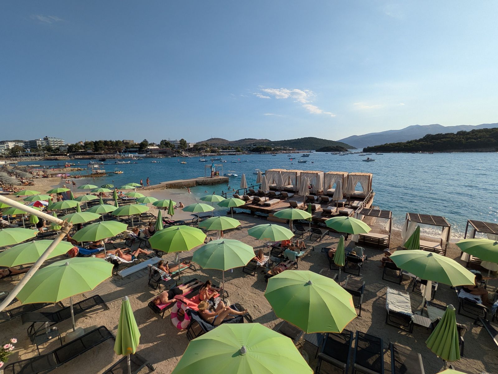 Playa de Ksamil llena de sombrillas verdes con los islotes al fondo