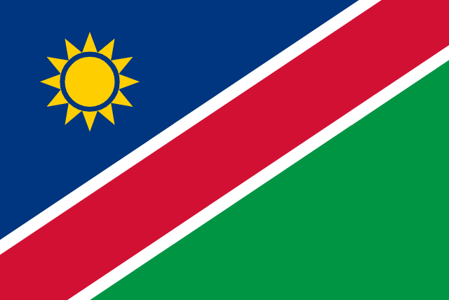 Bandera de Namibia: triángulos azul y verde separados por una franja roja ribeteada de blanco, con un sol amarillo
