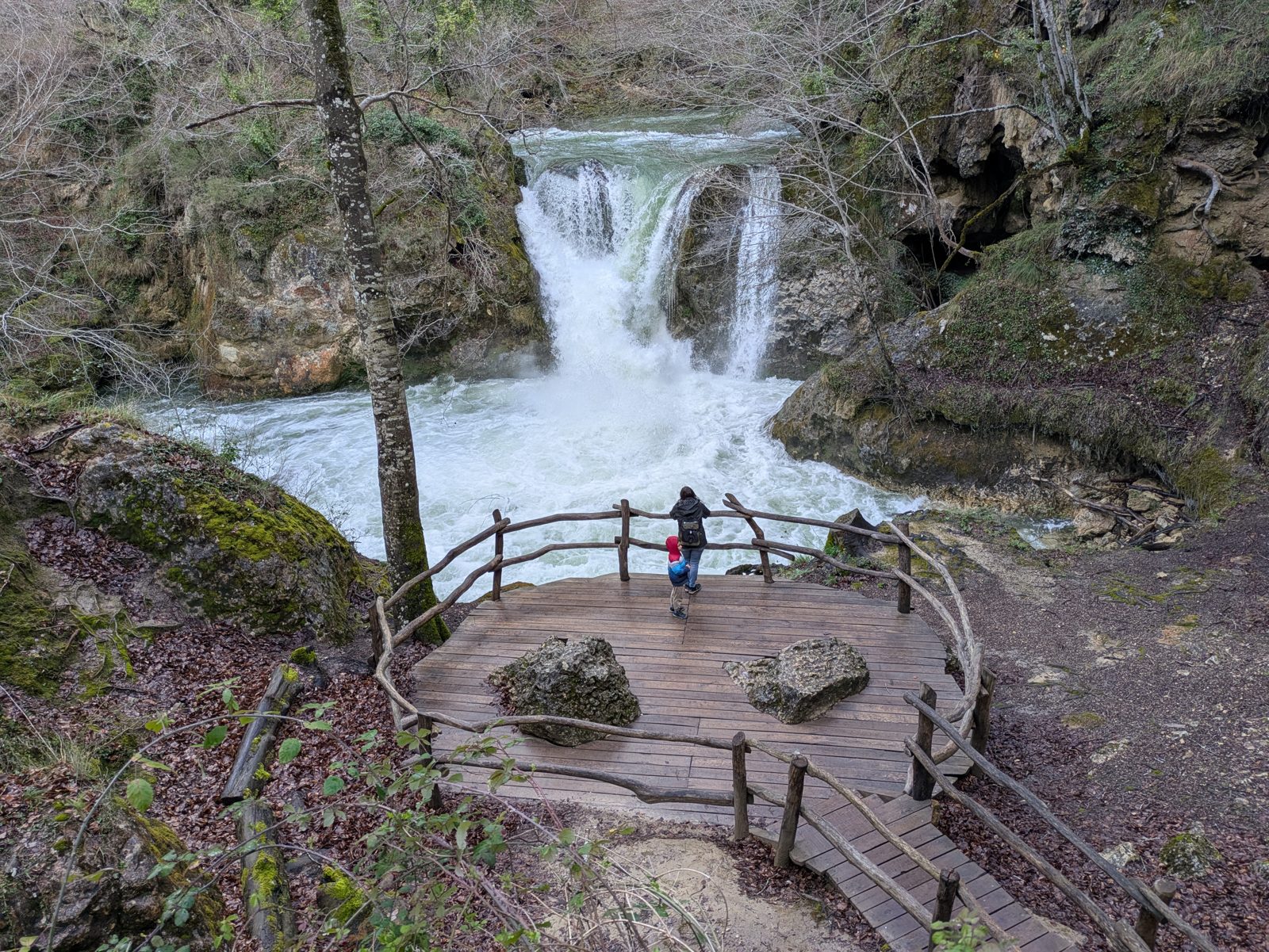 Cascada del Urederra y su mirador de madera vistos desde el camino, más arriba