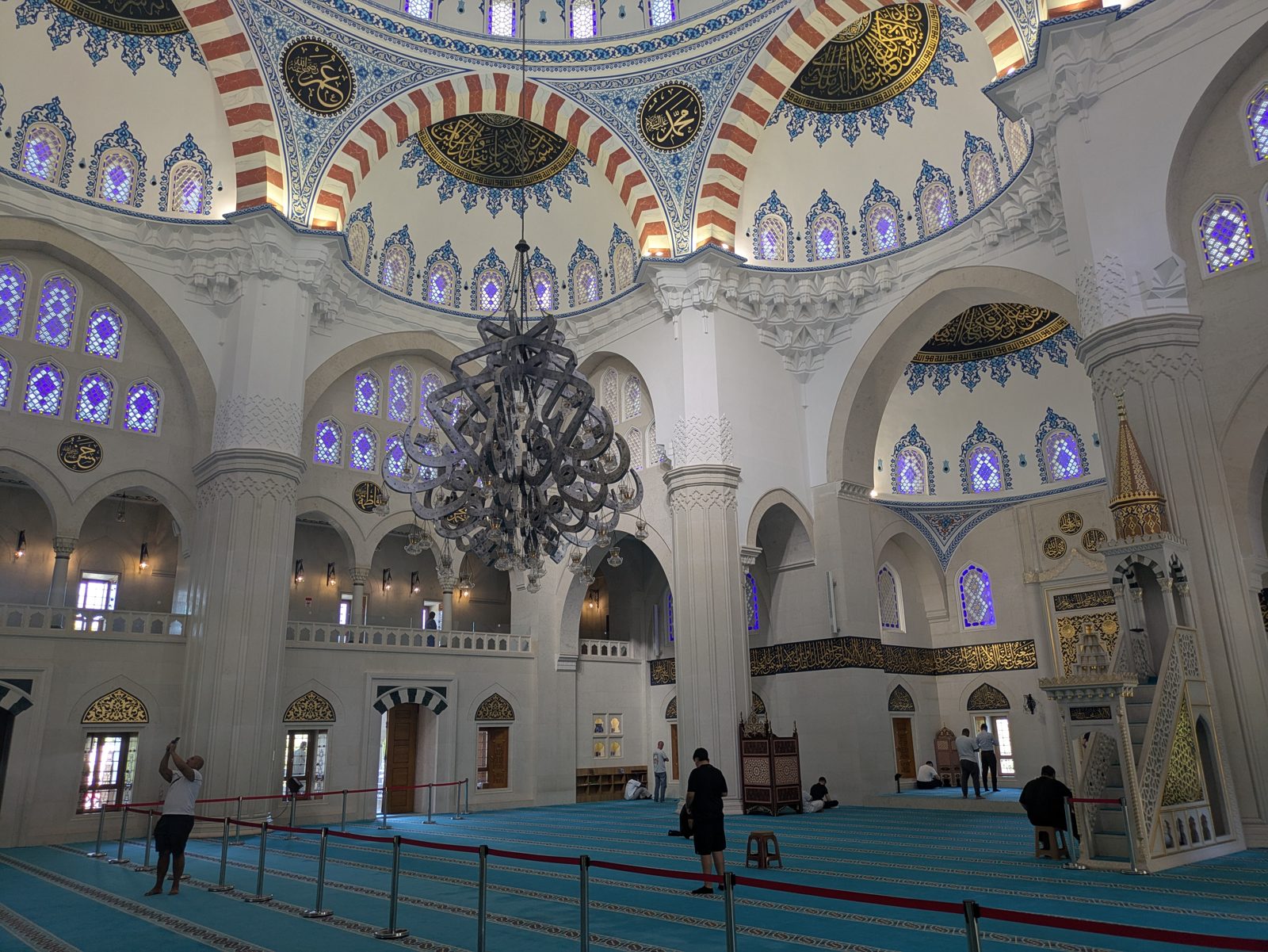 Interior de la Gran Mezquita de Tirana con cúpulas decoradas y una gran lámpara
