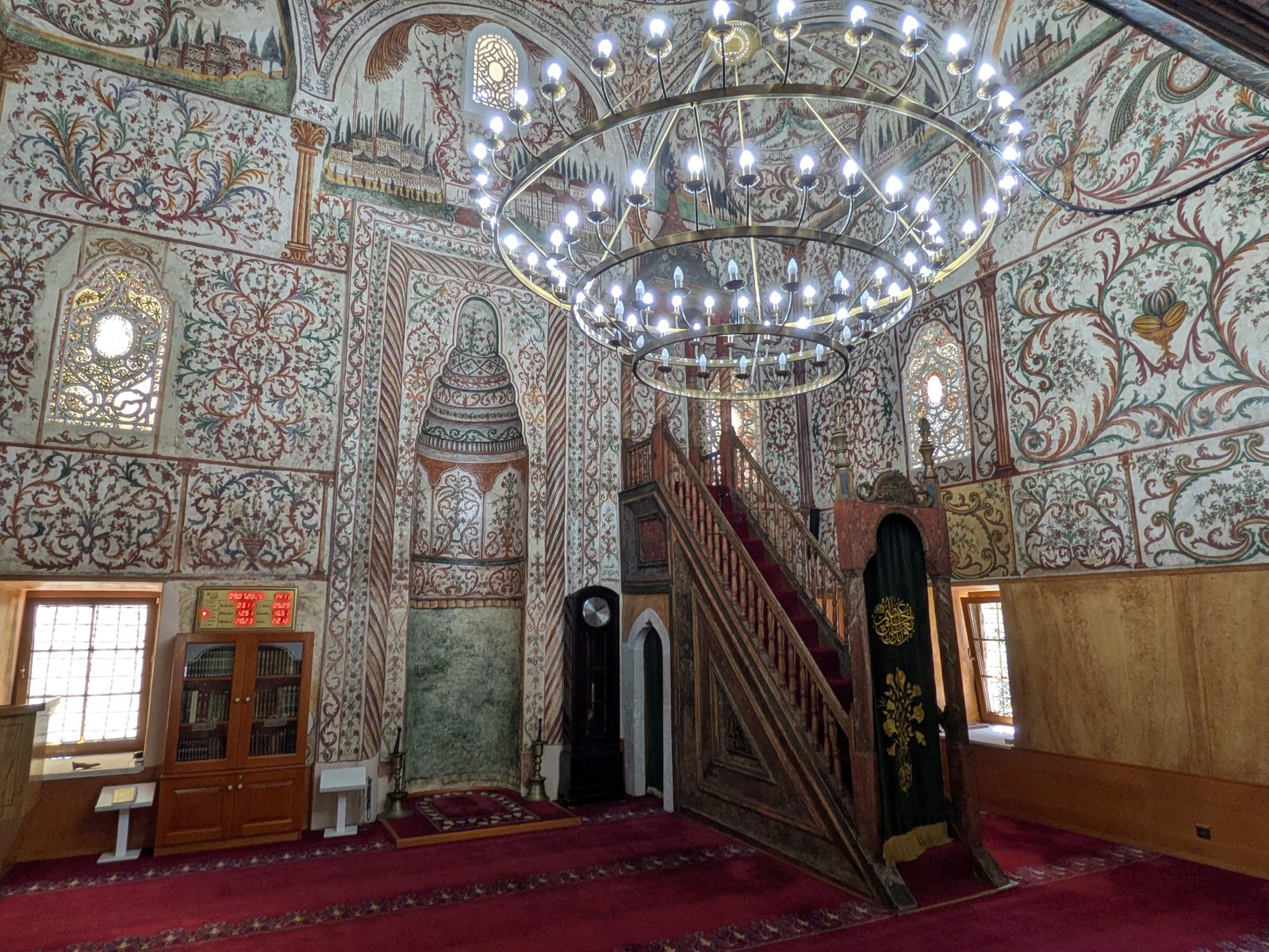 Interior de la mezquita de Et'hem Bey con las paredes cubiertas de frescos y una gran lámpara